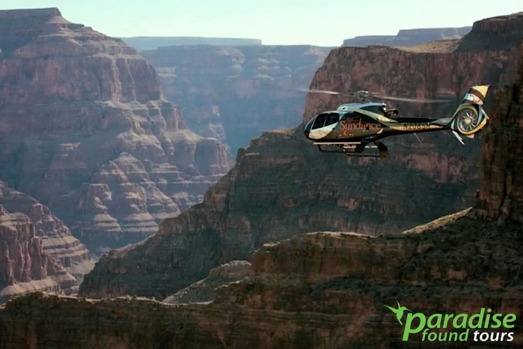 A helicopter flys into the chasm of the Grand Canyon West Rim.